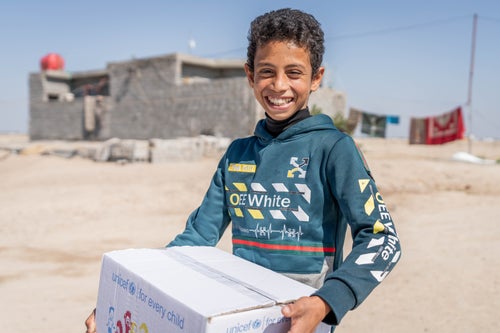 An boy in Iraq holds a UNICEF box of warm clothing