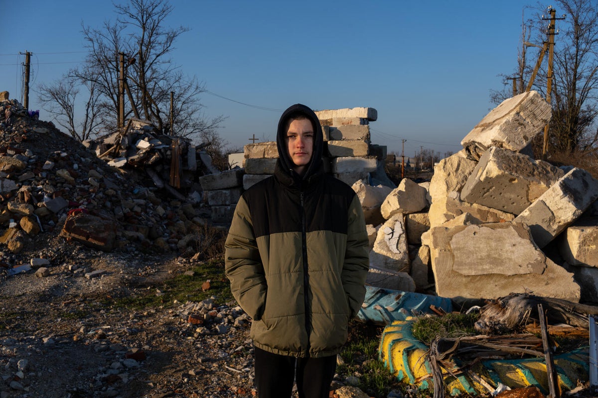 15-year-old David stands outside his destroyed school.  