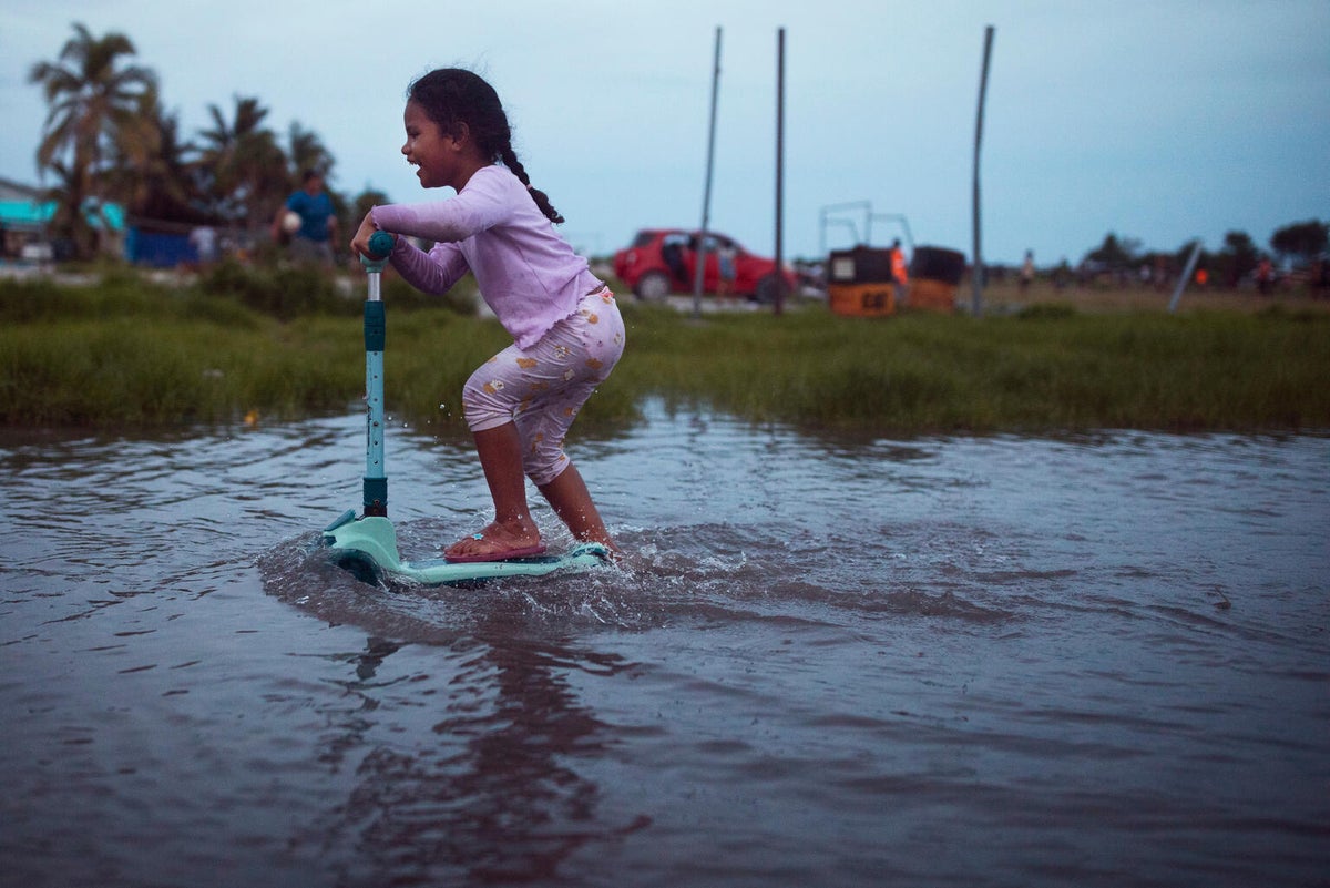 A child rides her scooter through floodwaters in Tuvalu.