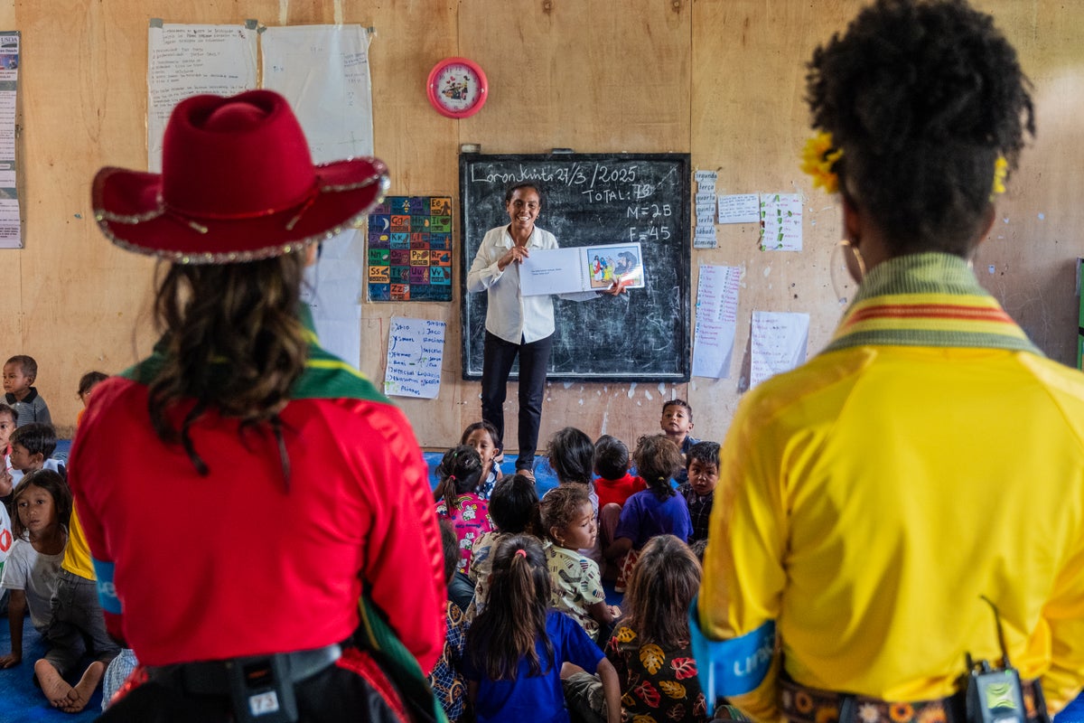 Two woman watching a teacher teach young students.