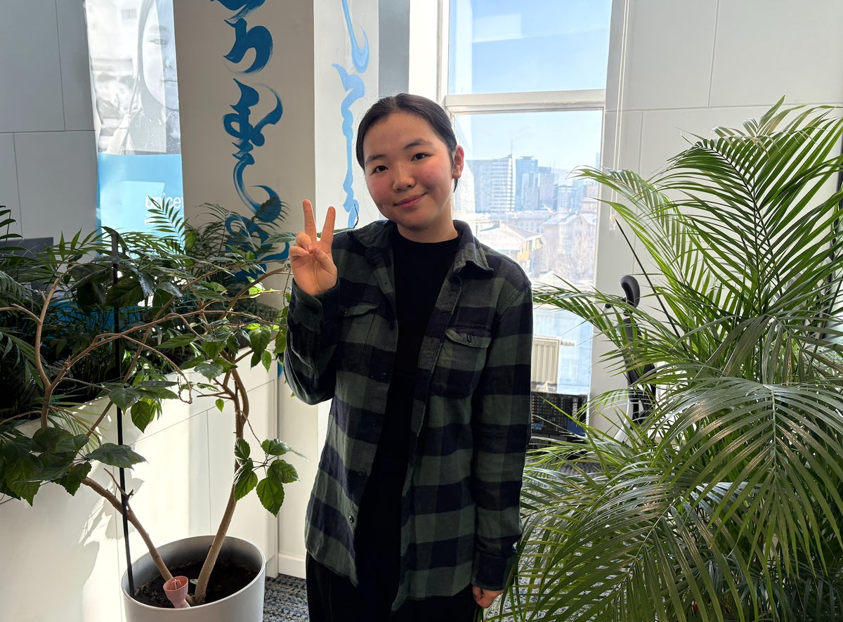A smiling girl holding her hands up in a peace sign.