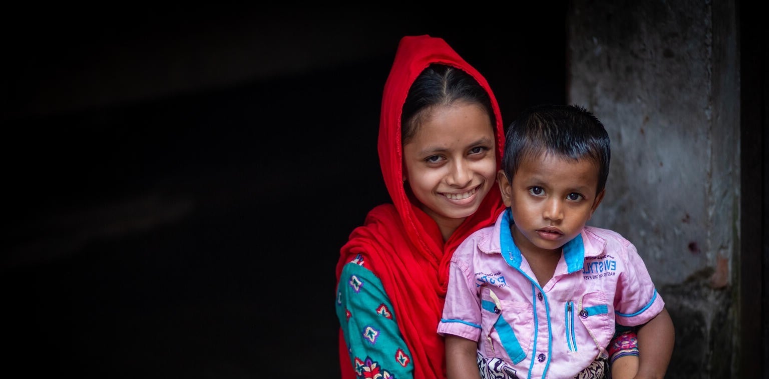 A young girl holds her brother in Bangladesh