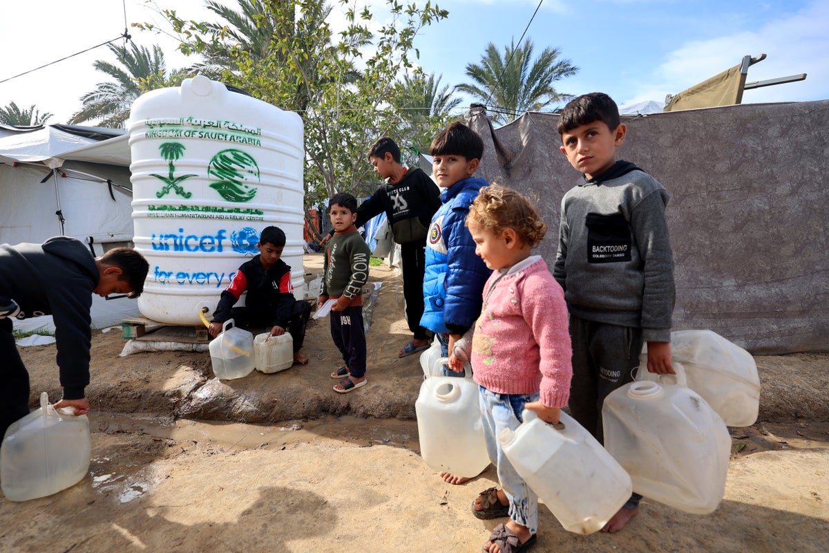 Children wait to collect clean water from a tank UNICEF helped install near a camp for displaced families in Gaza.