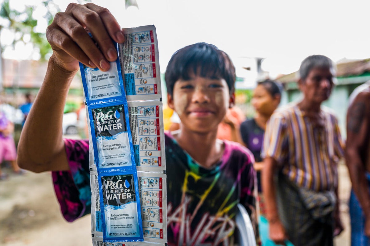 A boy shows packets of water purification sachets and tablets in Myanmar.
