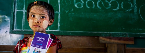 Thoon, 7, a Grade 2 student, holds earthquake awareness leaflets and other materials provided by UNICEF in a classroom in Myanmar.