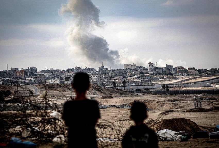 Two children from the south of Gaza watch smoke rise after an airstrike hit the centre of the city. 