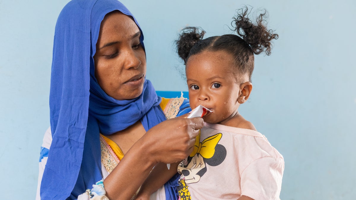 A mother is feeding Plumpy’Nut® to her 11-month-old daughter