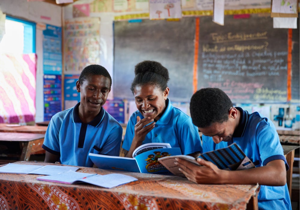 A girl and two boys looking at a book