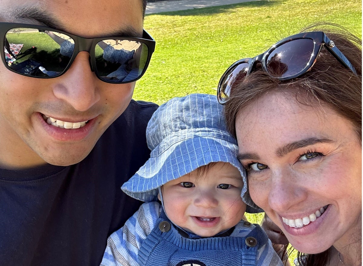 A couple poses for a selfie with their infant son. 