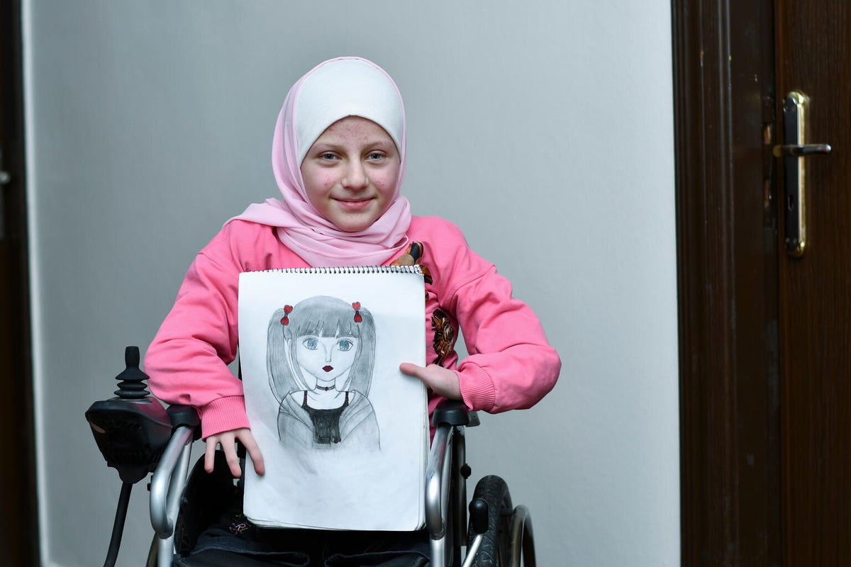 A young girl holding up her drawing. 