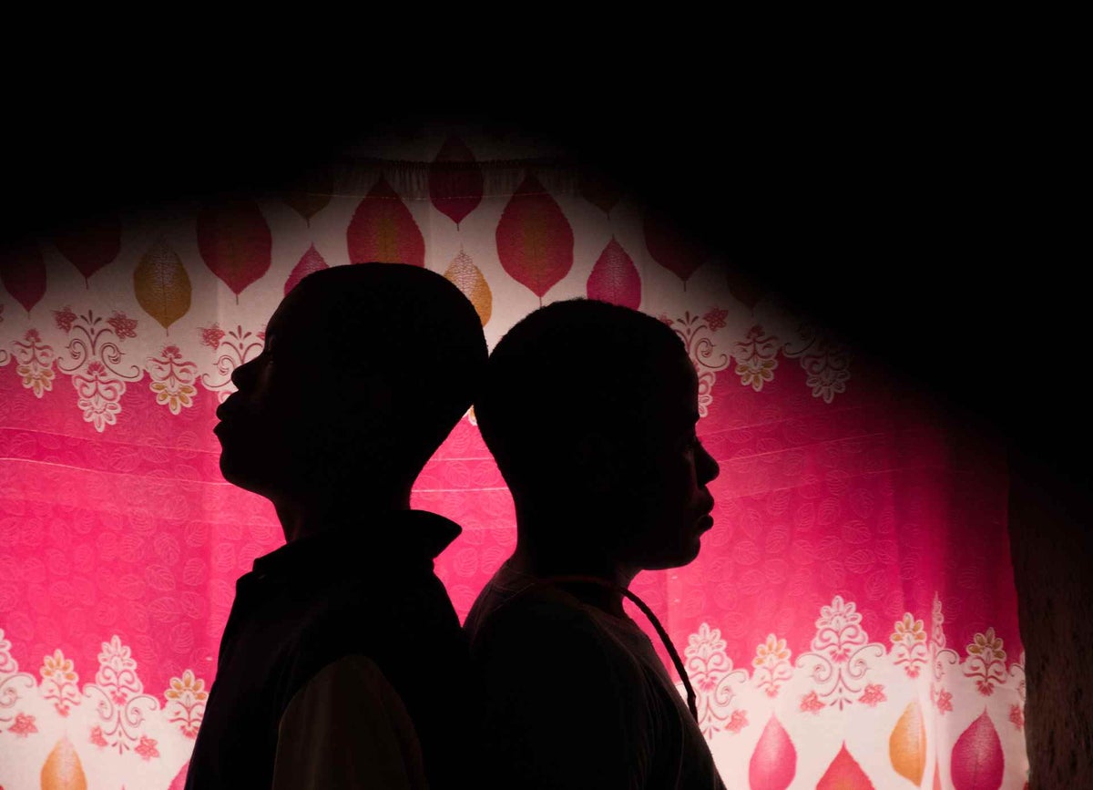 Two young men stand in the shadow. 