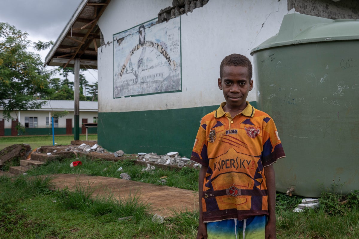 12-year-old student Jimmy stands in front of a classroom that was damaged by an earthquake in Vanuatu.