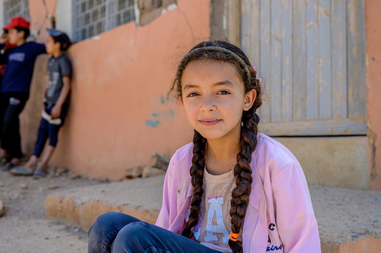 A 10-year-old girl sits near a damaged classroom in Morocco following the earthquake that struck in September 2023.