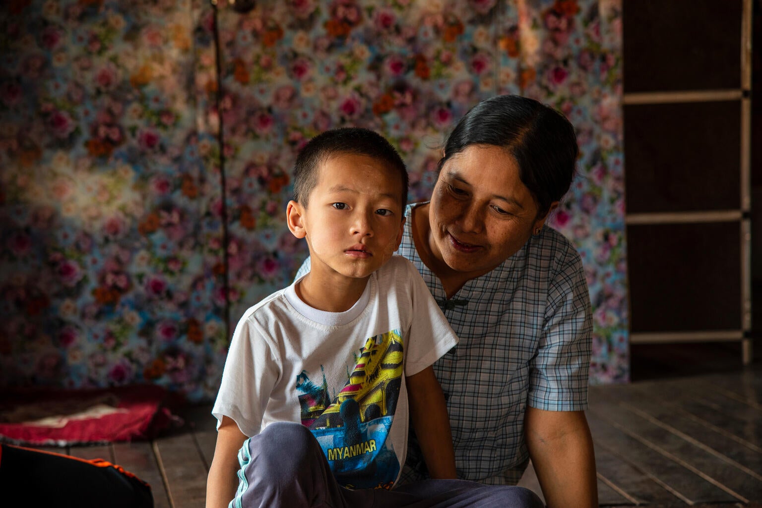 A child living with disability sits with his mother at their home in Myanmar