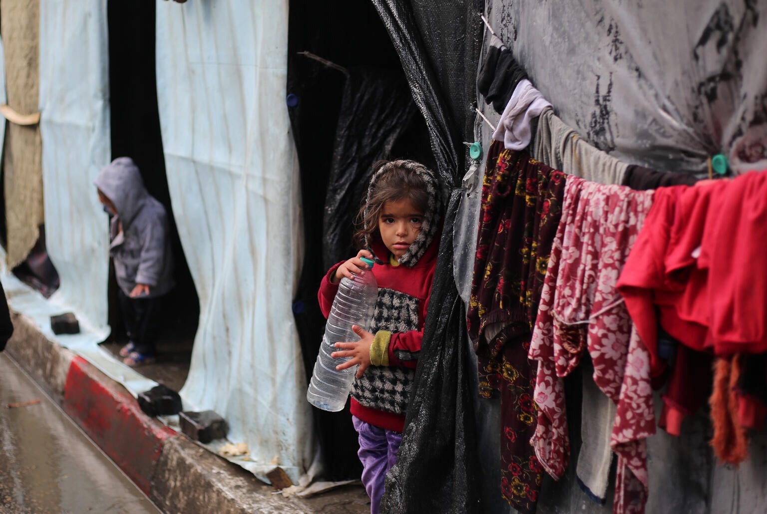 Girl standing outside temporary shelter in the Gaza Strip conflict.