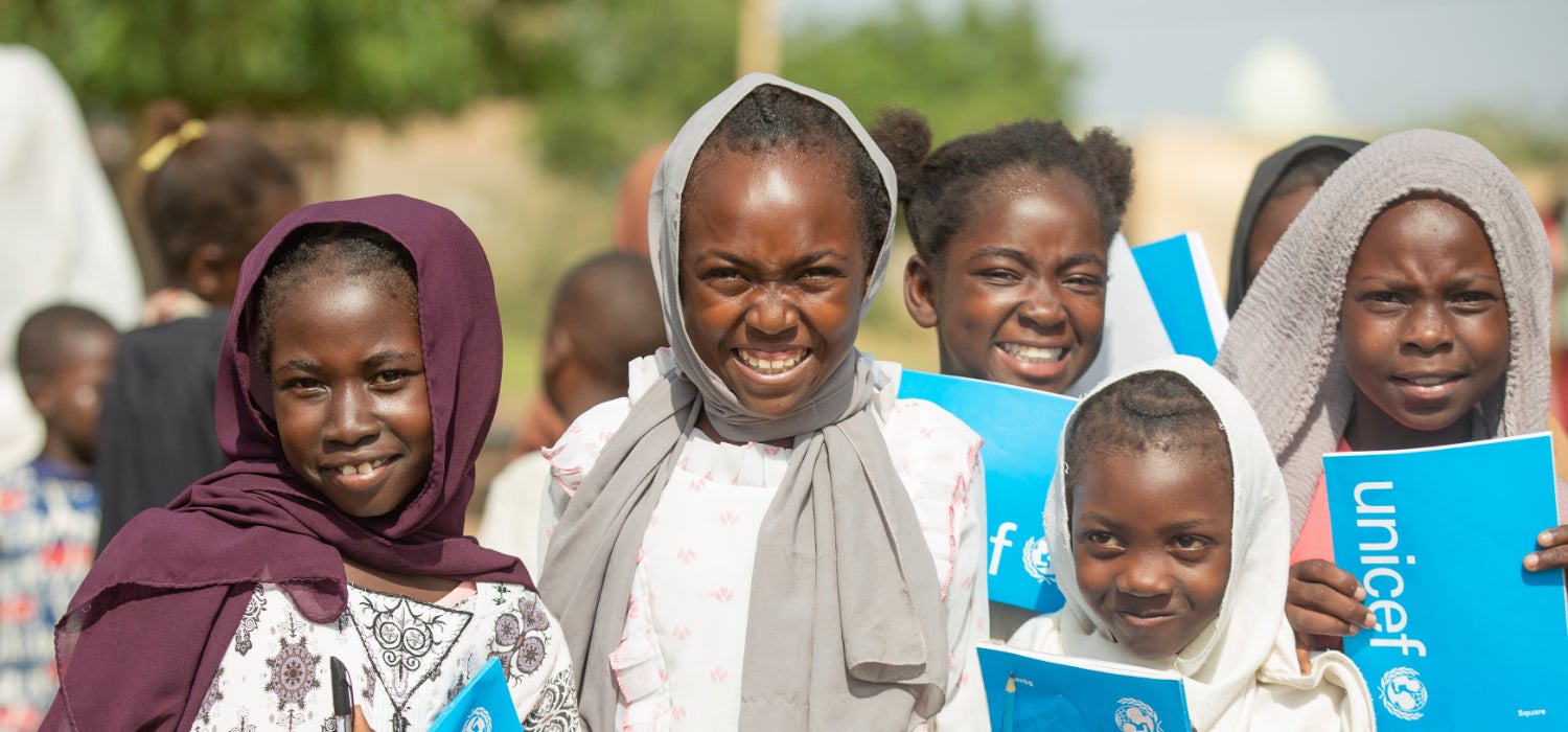Displaced children with UNICEF exercise books at a safe learning space in Sudan.