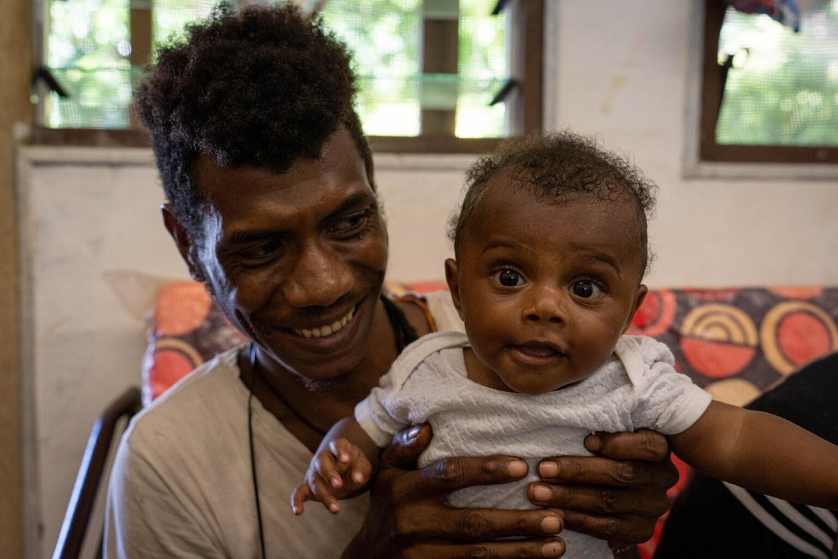 A smiling father holding up his newborn.