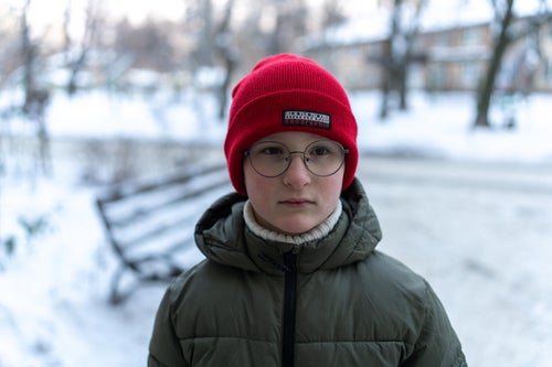 Eight-year-old Yehor stands outside his home, after returning with his mother from a shopping centre where they went to charge phones and warm up during power outages.