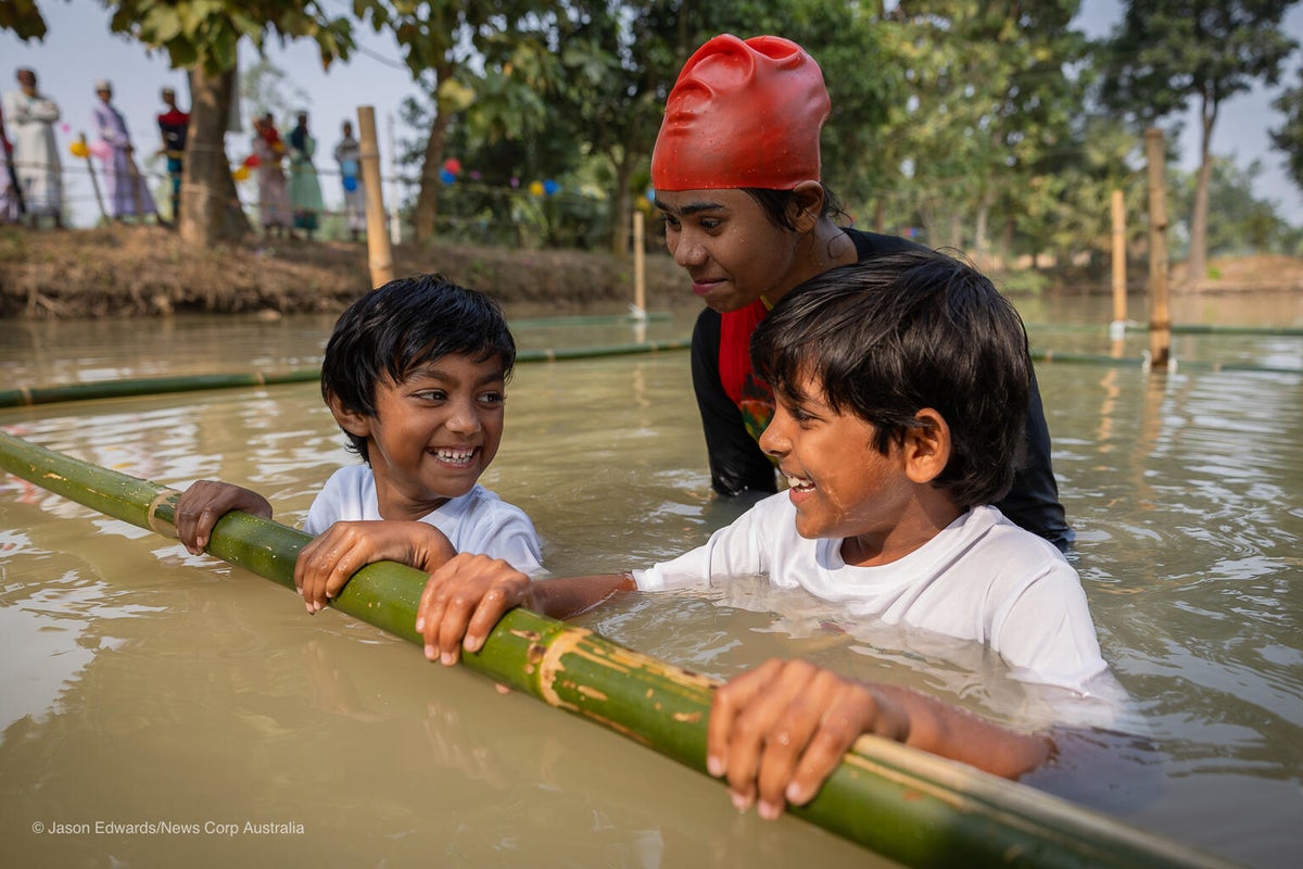 A young woman teaches two children how to swim as part of the Swim Safe program. 