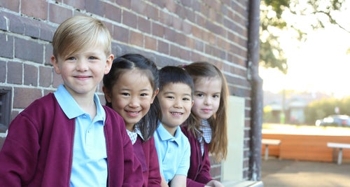 A group of four schoolchildren pose for a photo in a schoolyard. 