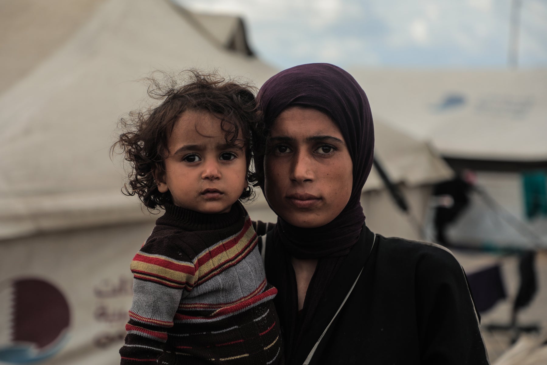 A mother holds her child in Gaza. Displaced families continue to face harsh conditions after losing their homes.