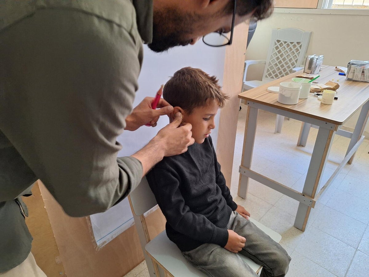 A young boy in Gaza is fitted with a hearing aid.