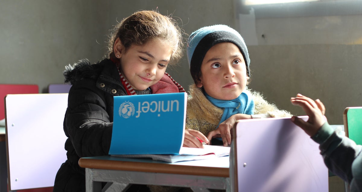 Two children sit in class doing work