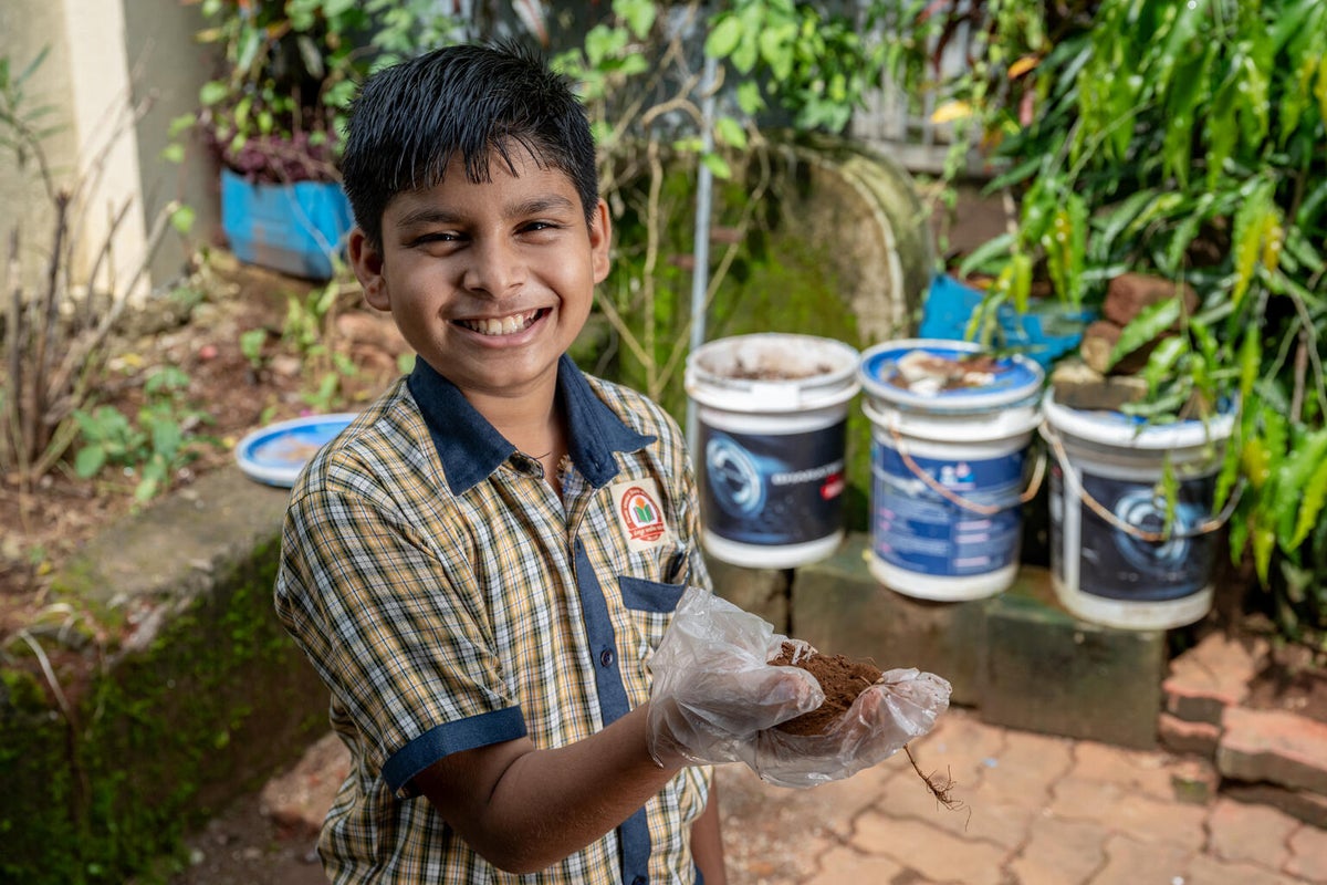 A young boy holding compost in his hands at school. 