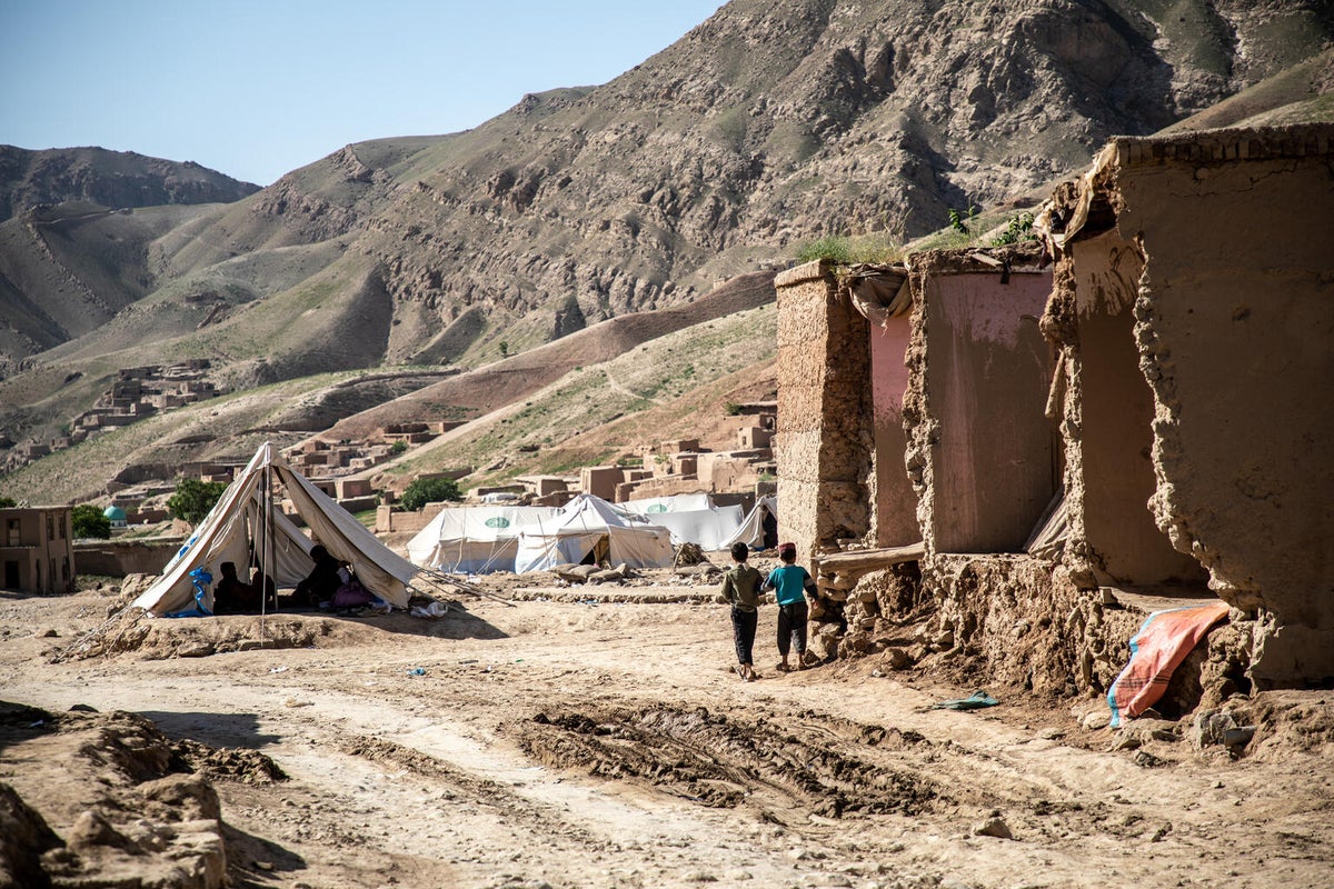 Two children walk towards a collection of tents in a flood-affected village in Afghanistan.