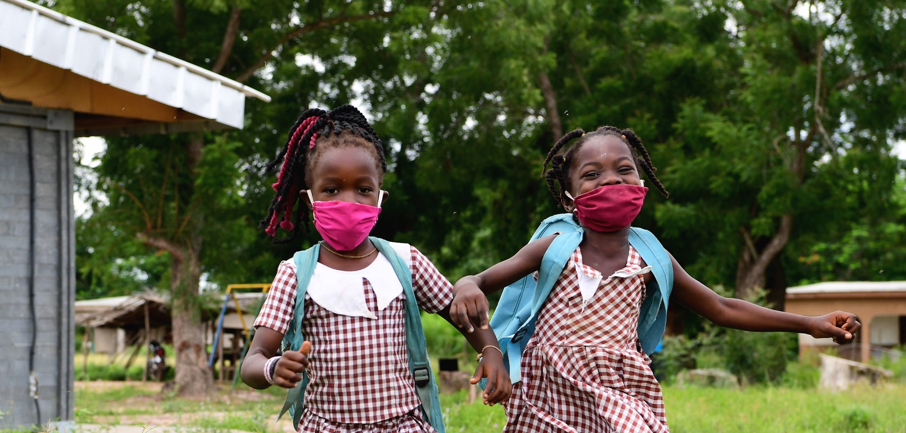 Two school girls wearing masks and running happily