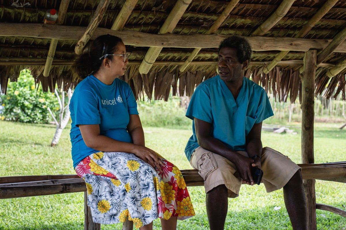 A woman in a UNICEF shirt talking to a health professional. 