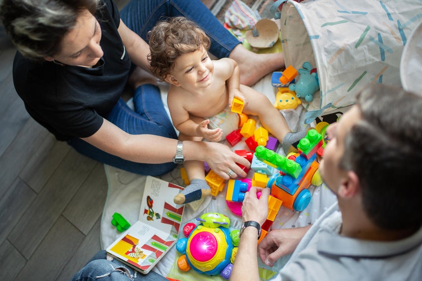 A father and mother are playing with their two-year-old son.