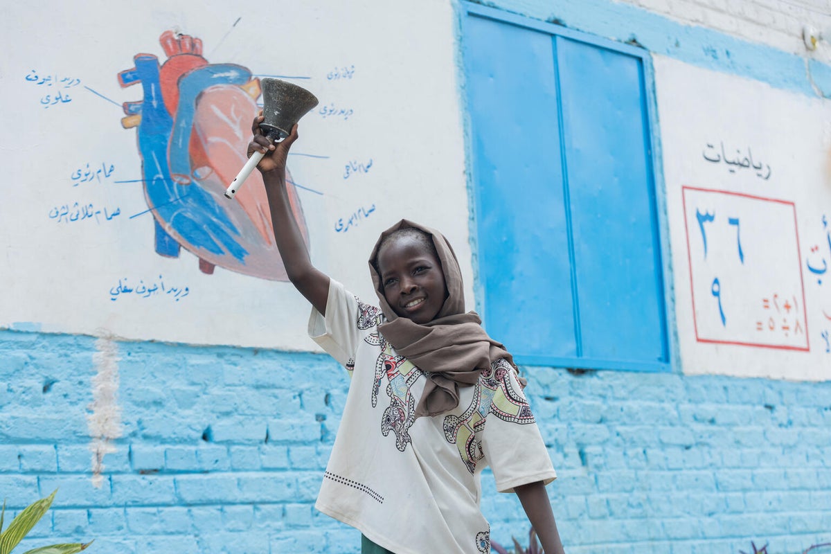 At break time, 11-year-old Rabha rings the bell at the UNICEF-supported safe learning space in Sudan.