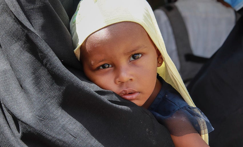 A young girl in Sudan being held by her mother.