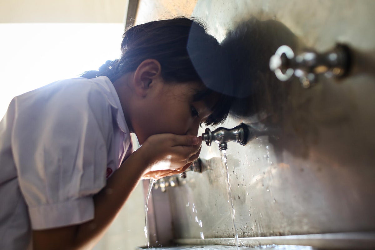 Pimchanok drinks water from a tank at her school.