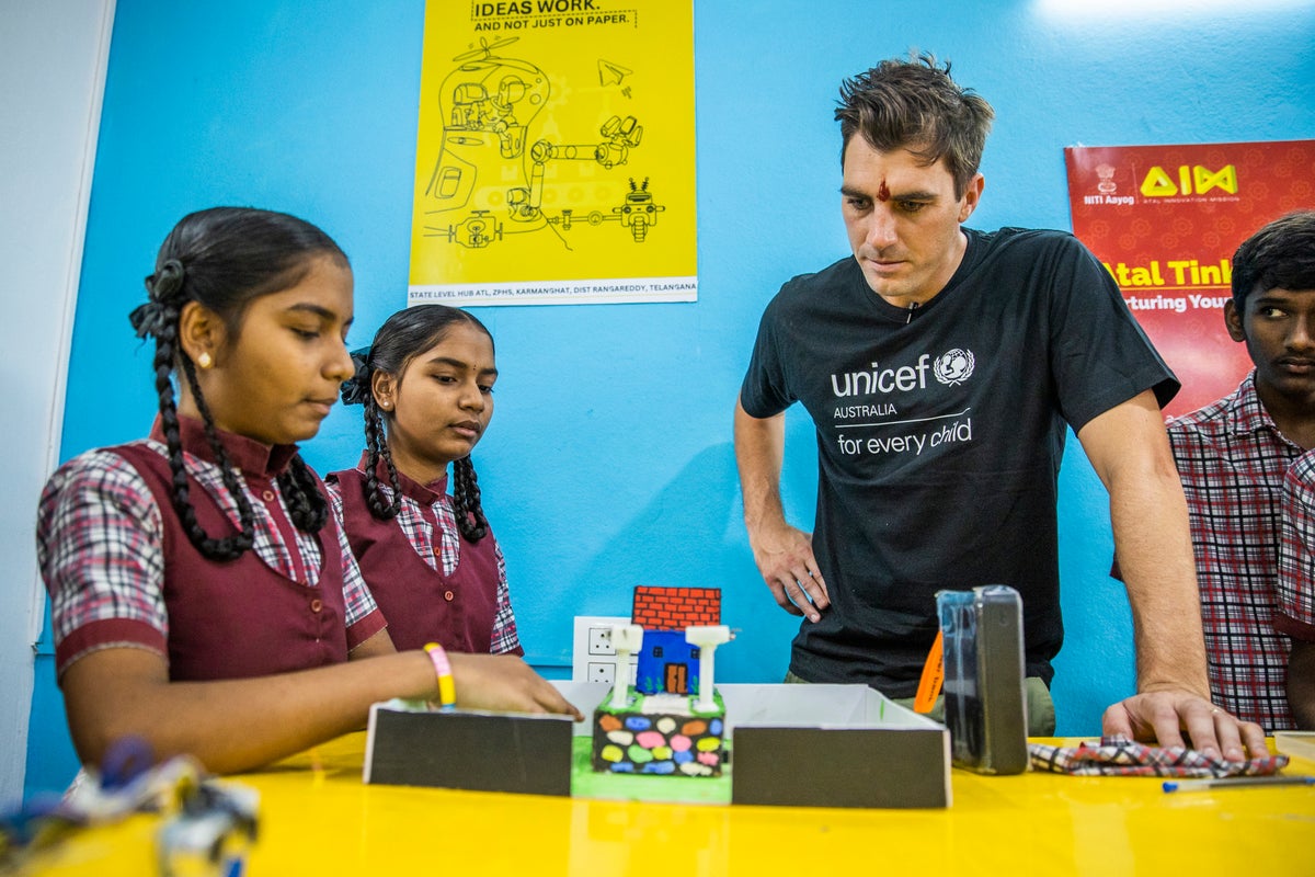 Pat Cummins examines a mini house model created by a young student in India. 