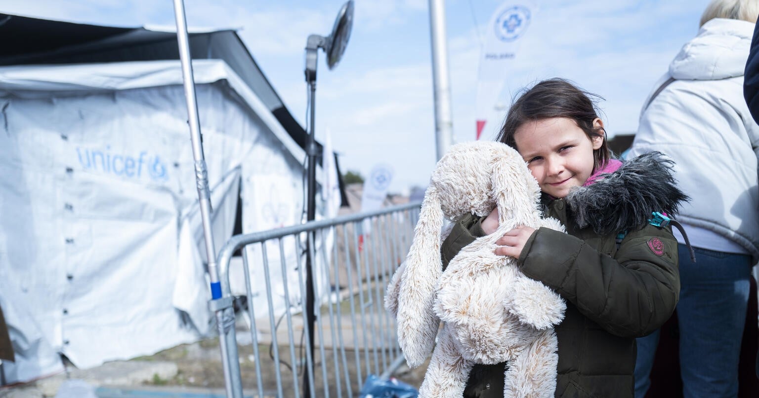 A young girl carrying a UNICEF box.