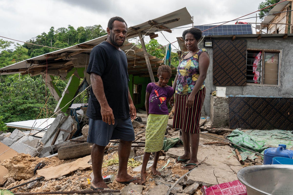 A family stands in front of their destroyed home in Vanuatu