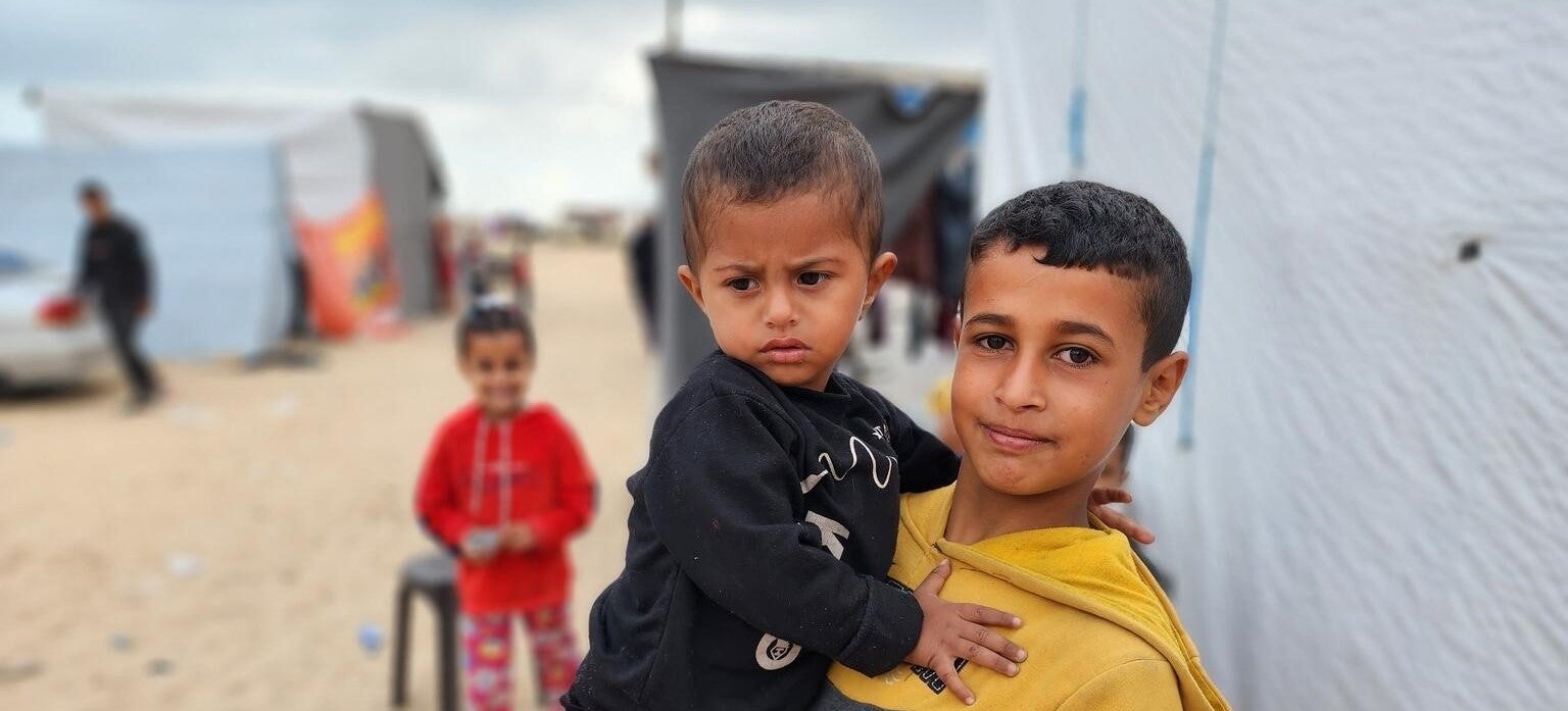 Two young brothers outside their temporary home at a displacement camp in the Gaza Strip.