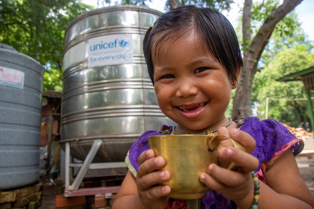 Three-year-old Shwe drinks clean water from a safe drinking water tank provided by UNICEF in southeast Myanmar. 