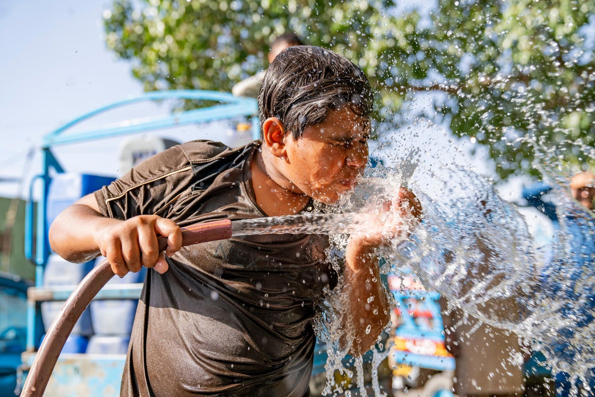14-year-old Javaid drinks water directly from a water pipe in the 47 °C hot weather in Punjab, Pakistan. 