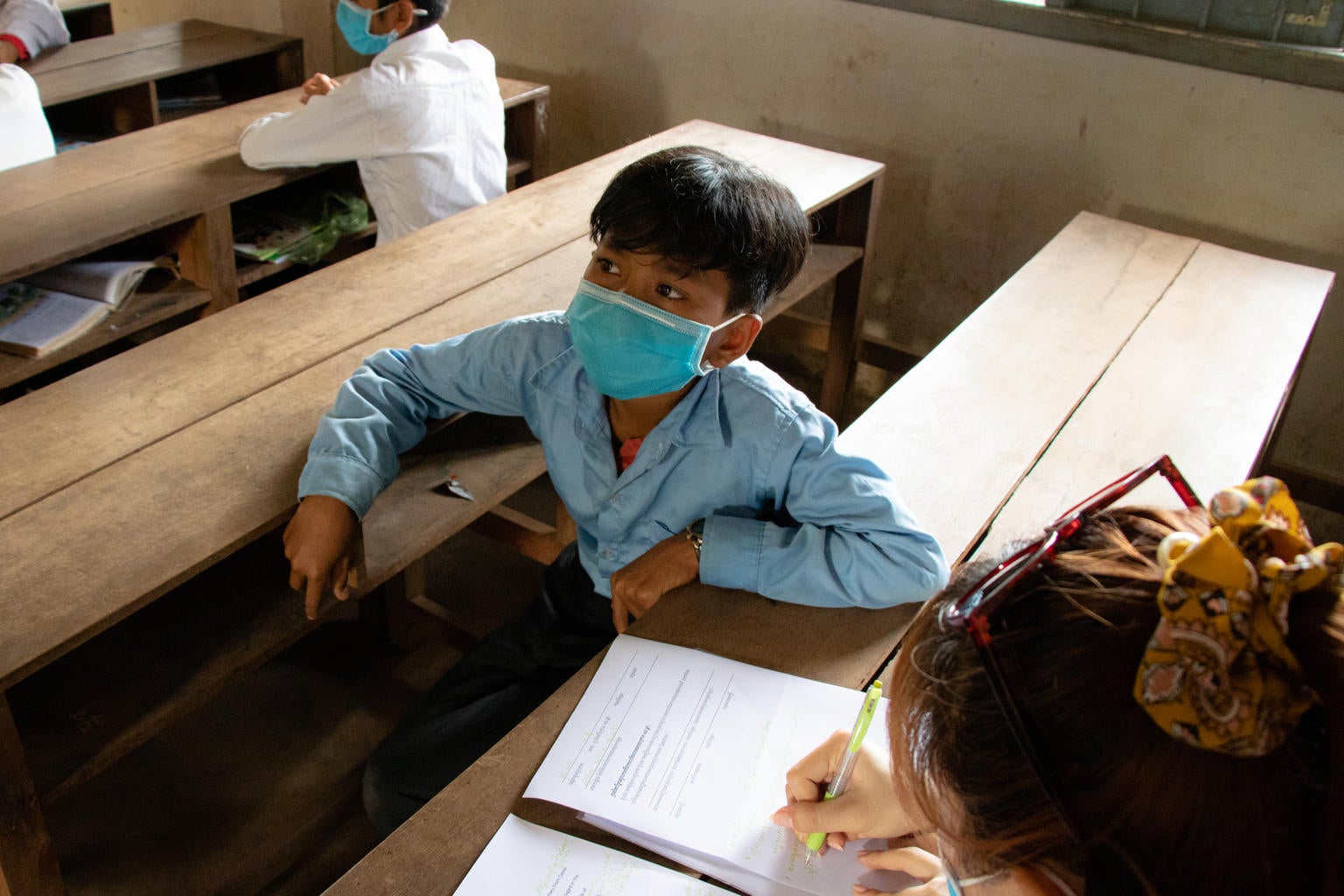 A UNICEF staff member talks to Saev Yes, a 12 year old student at Ler Touch Community school