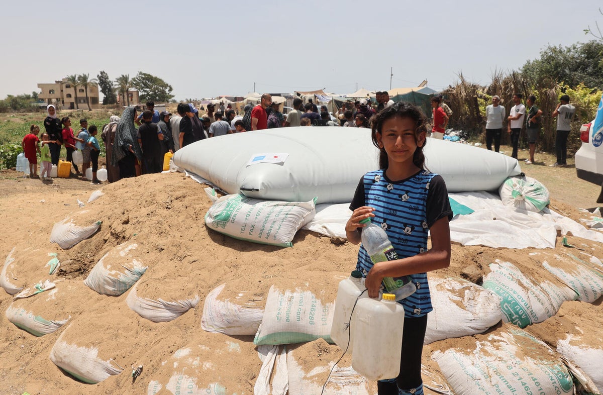 An 11-year-old girl holds jerrycans and a bottle filled from the UNICEF-supported water tank in the Gaza Strip. 