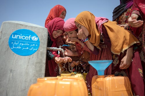 A group of girls drink water from a tap in a village in Afghanistan. 