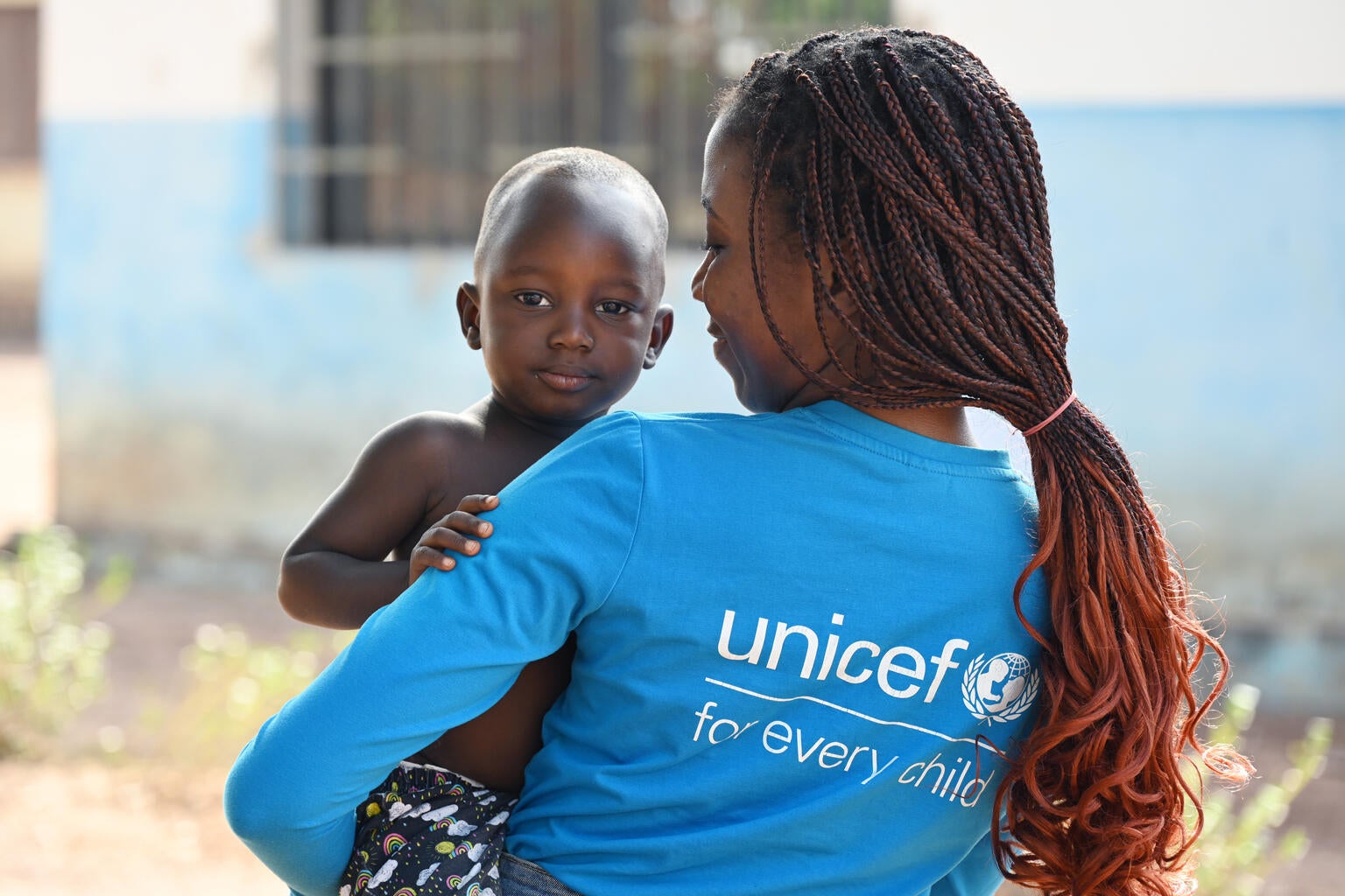 A UNICEF worker supporting a young child.