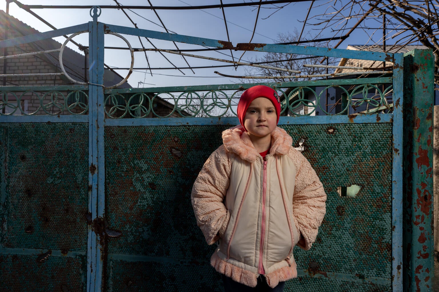 A young girl stands in front of her damaged home in Ukraine.