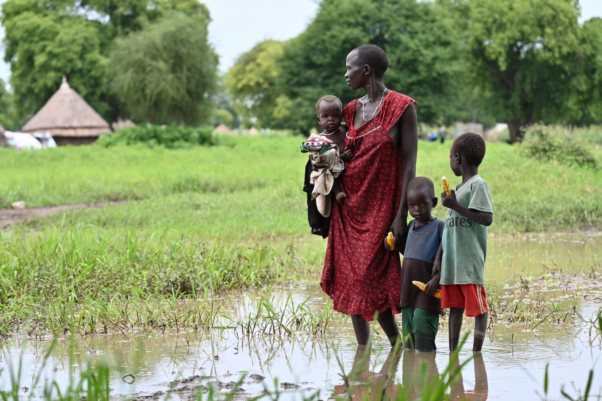 A woman and her children stand outside their flood-damaged home in Ethiopia.