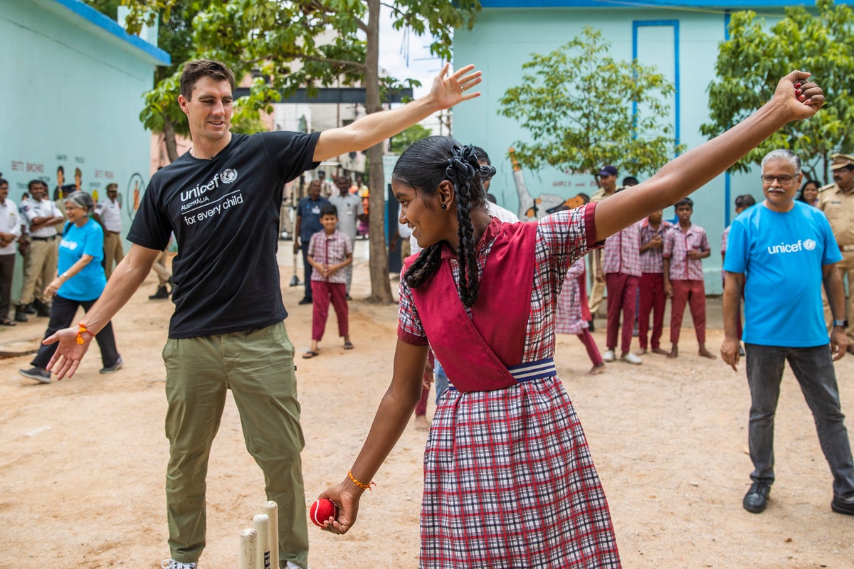 Pat Cummins shows a schoolgirl how to bowl during a game of cricket. 