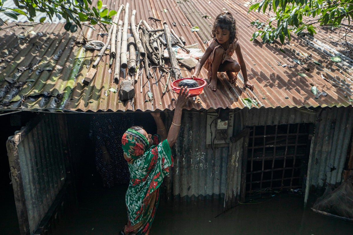 A mother lifts her daughter to the roof of their flooded home in Bangladesh.