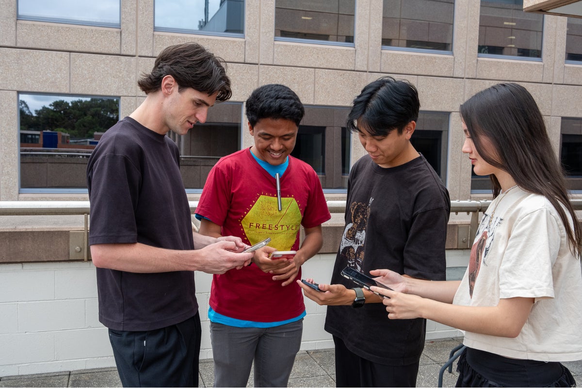 A group of young adults play on their phones together. 